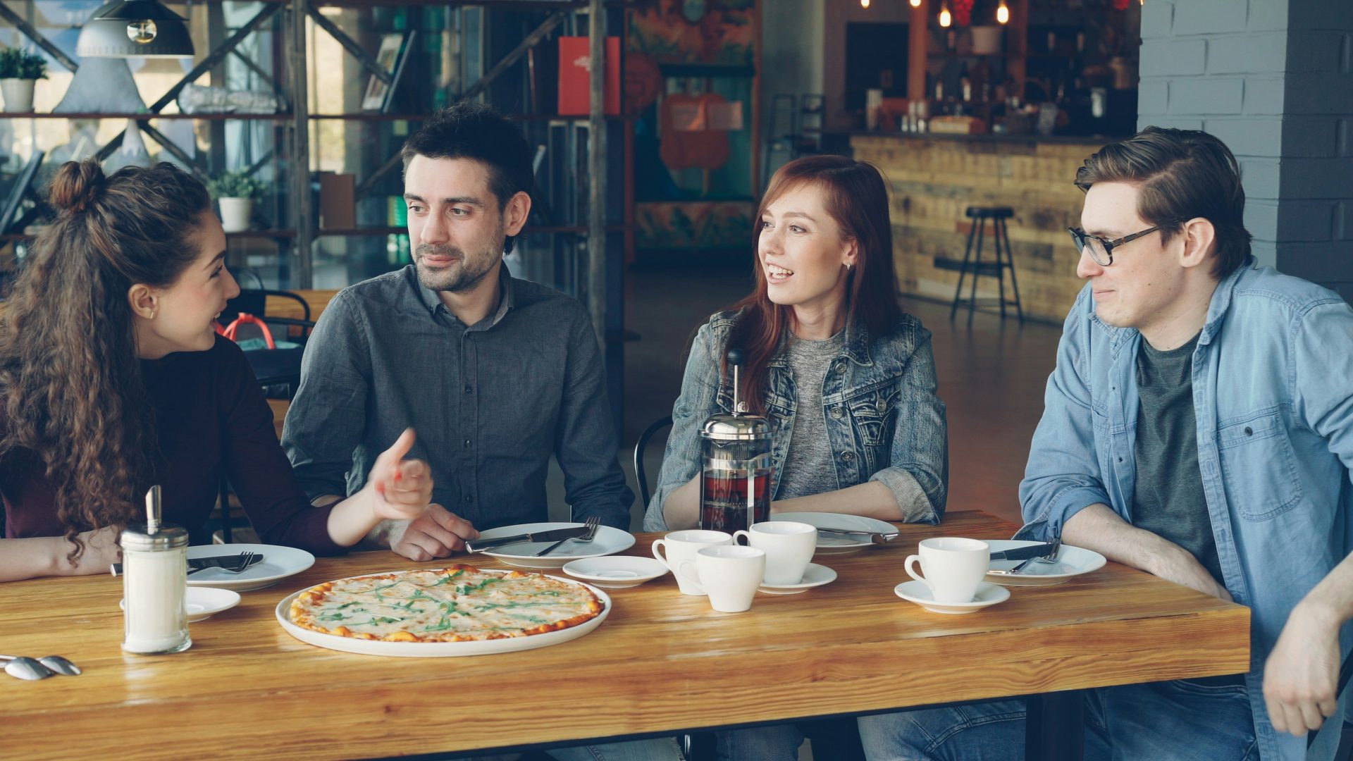 Friends enjoy pizza and conversation in a restaurant.