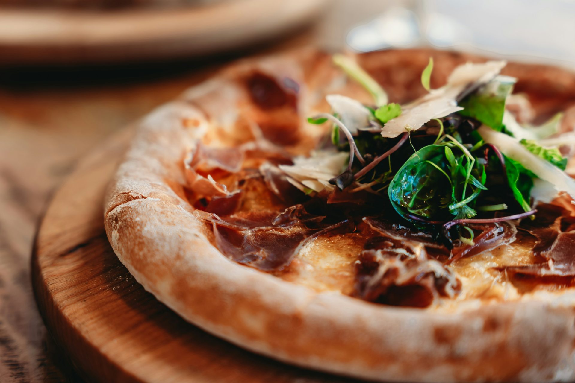 A gourmet pizza with prosciutto and fresh greens